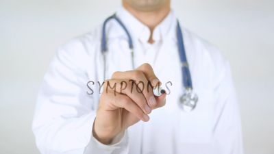 Doctor writing 'symptoms' on transparent board.
