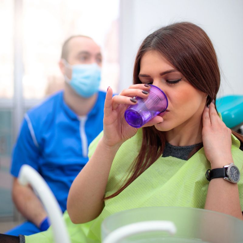Young woman washing mouth at dentist's officeYoung woman washing mouth at dentist's office