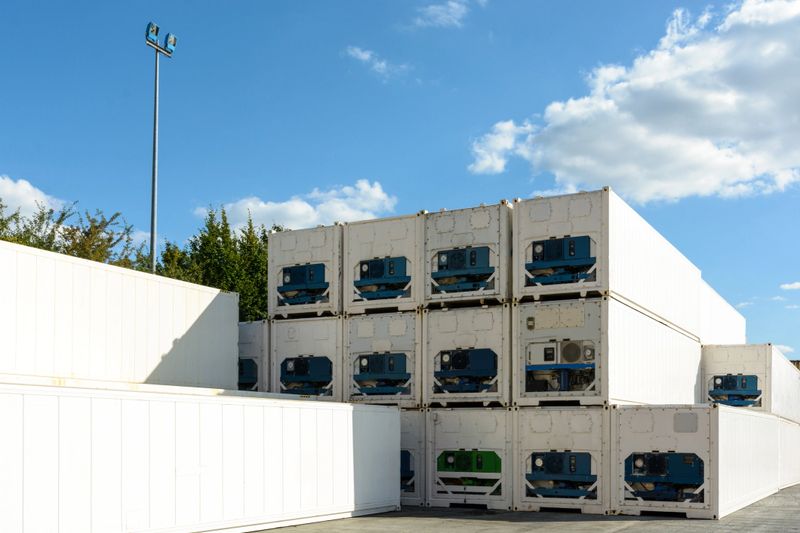 Dozens of immaculate white refrigerated containers stacked in the sunlight in a shipping yard in the region of Paris.