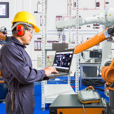 Engineer programs robotic arms in a high-tech industrial setting.