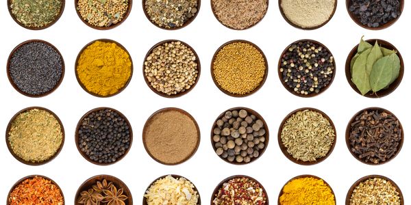 Rows of various colorful spices and herbs in small bowls.