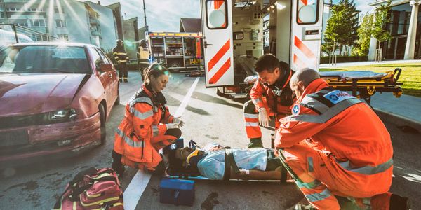Paramedics attend to a car accident victim on the street.