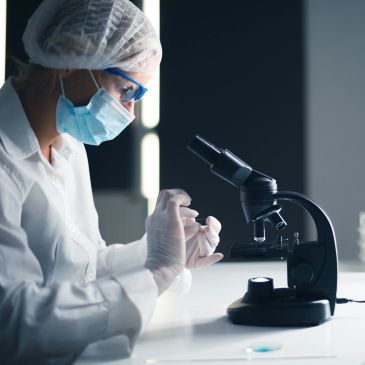 Scientist working with microscope in lab.