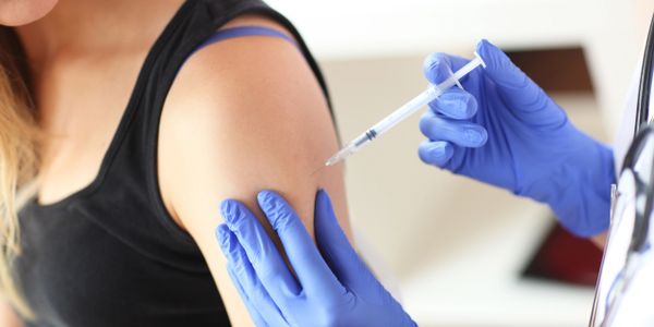 A person receiving a vaccine injection in the upper arm.