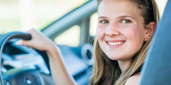 Young woman smiling while driving a car.