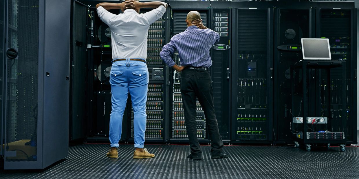 Two men observing server racks in a data center.