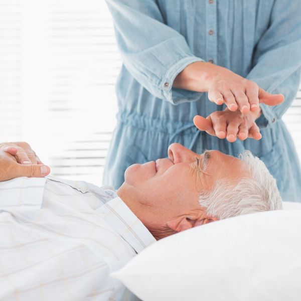 Man receiving Reiki from a woman dressed in blue