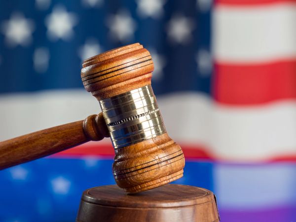 Wooden judge gavel with American flag background.