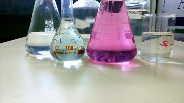 Various laboratory glassware with colored liquids on a table.