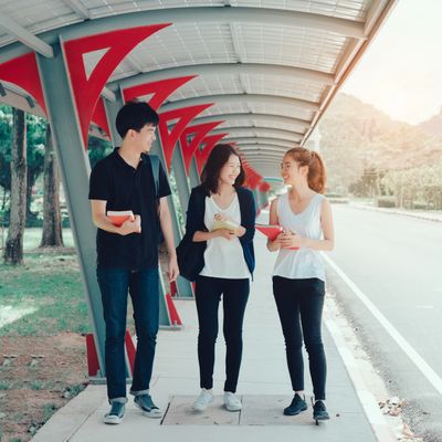 Three young people walking and chatting under a covered walkway.