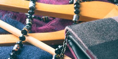 Close-up of clothes hangers with dark bead necklace and folded fabric.