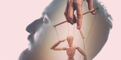 Man's profile with puppet strings controlled by a hand.