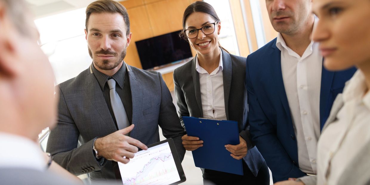 Business professionals discussing data using a tablet and smartphone in a modern office.