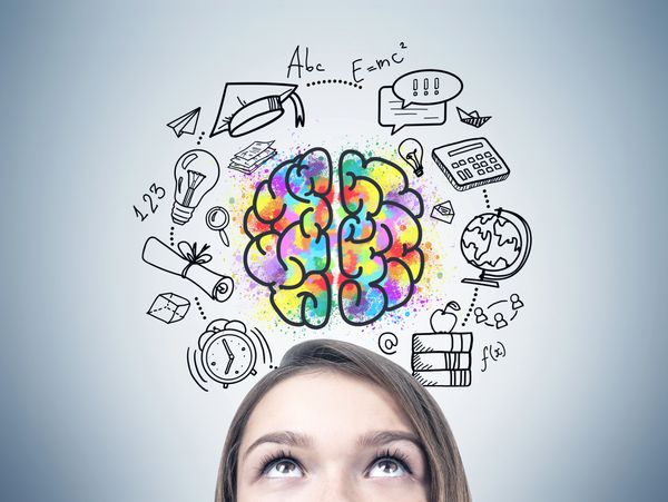 Young woman looking up at colorful brain with education icons around it.
