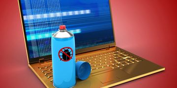 Bug spray can placed on a laptop keyboard with a warning symbol.