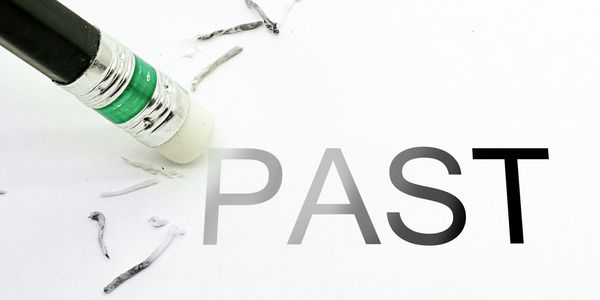 A pencil eraser partially erasing the word "PAST" on white paper. expungement.