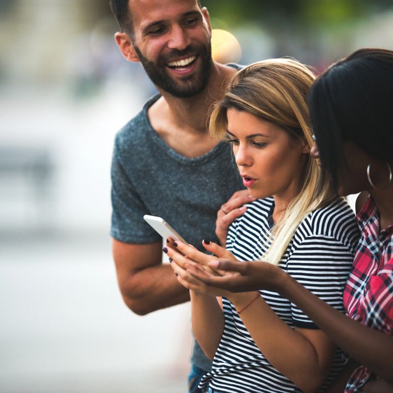Group of friends using phone in the city.