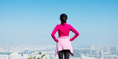 Woman in pink jacket overlooking a cityscape from a high vantage point.