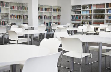 Empty library reading area with white tables and chairs.