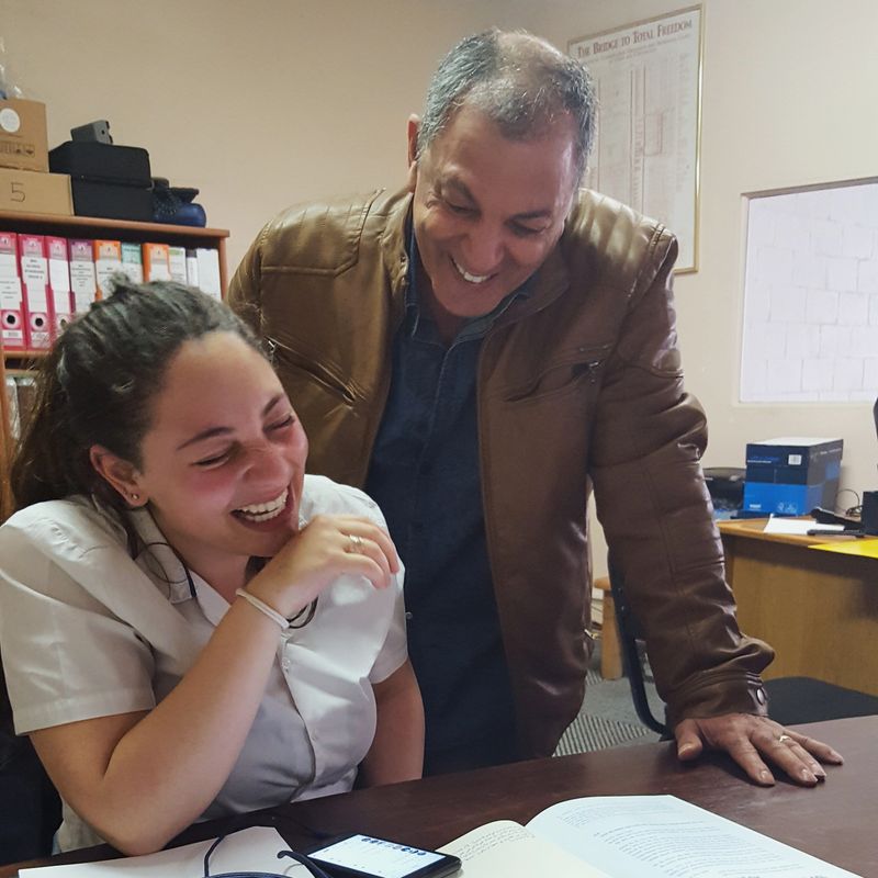 Cropped shot of a teenage girl showing her dad a text message while studying