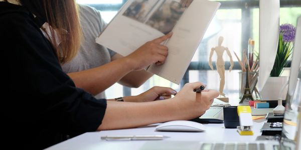 Two people in an office looking at some proofs one is pointing and one is holding a pen.