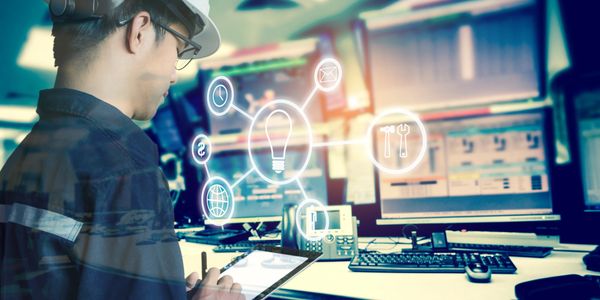 Engineer using a tablet with digital icons in a control room.