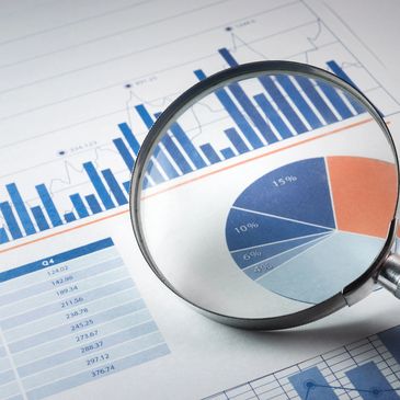 Magnifying glass over financial charts and pie graph.