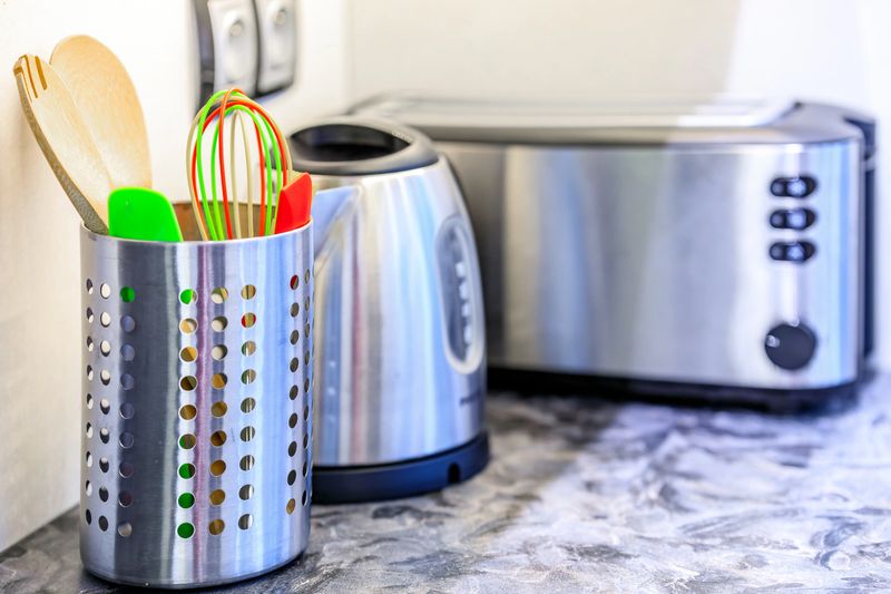 Colorful kitchen tools and stainless steel appliances in a modern kitechen on a marble countertop