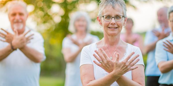A group of people doing Tai Chi together flowing through a posture called Crossing Hands.