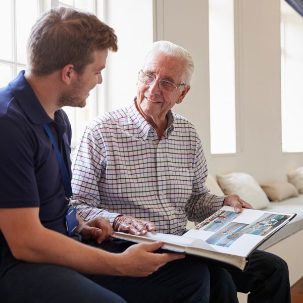 Young man and elderly man looking at a photo album.