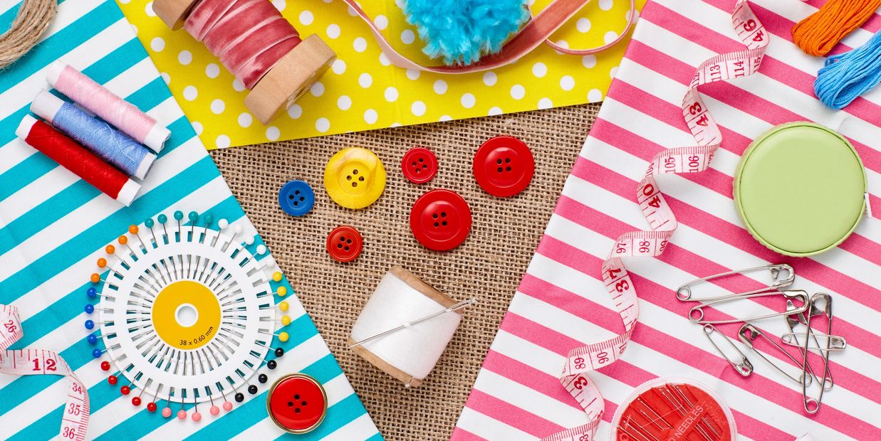 Colorful sewing supplies arranged on striped and polka dot fabric backgrounds.