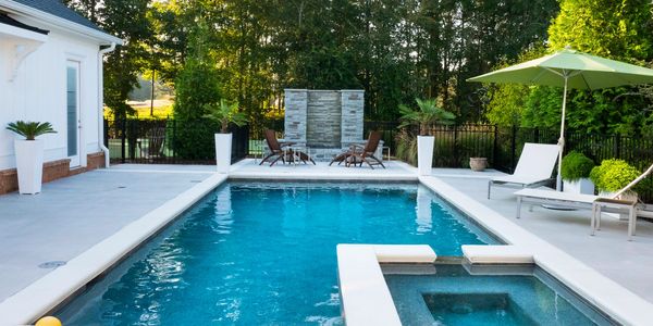 Modern backyard pool with lounge chairs and water feature in a serene setting.