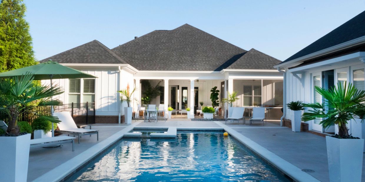 Modern house with a backyard pool and patio seating.