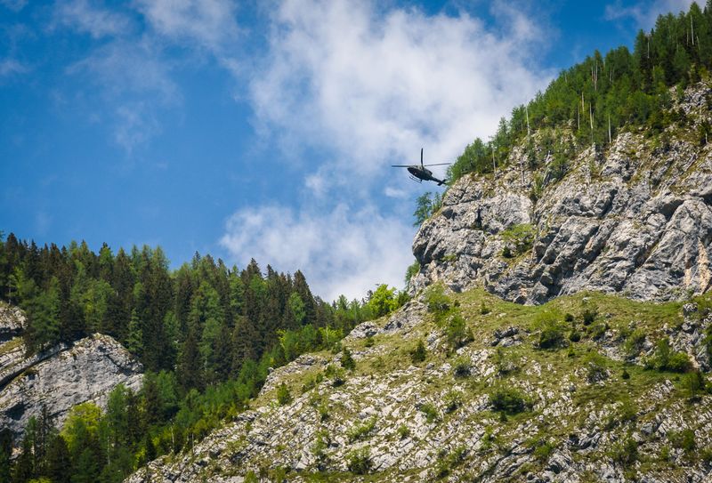 Army helicopter preforming a rescue in the mountains. Hovering chopper is attending in mountain accident over Komarca in Slovenia.