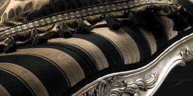 Close-up of vintage black and gold striped sofa with detailed carvings.
