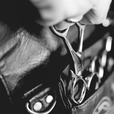 Hand holding hairdressing scissors in black and white.