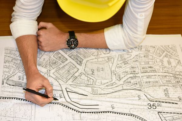 Engineer working on a detailed map or blueprint.