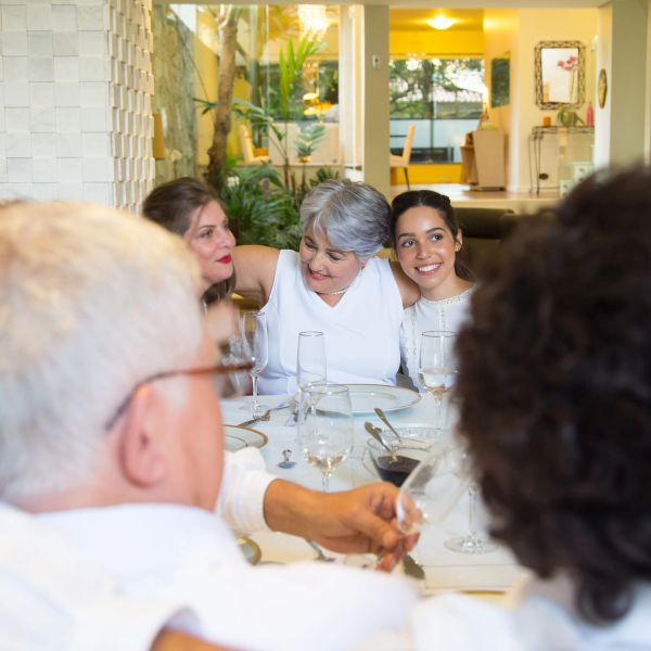 Family gathering at dining table with three generations sharing joyful moments.