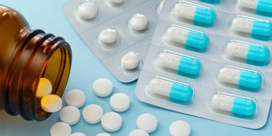 White tablets and blue capsules with pill bottle.
