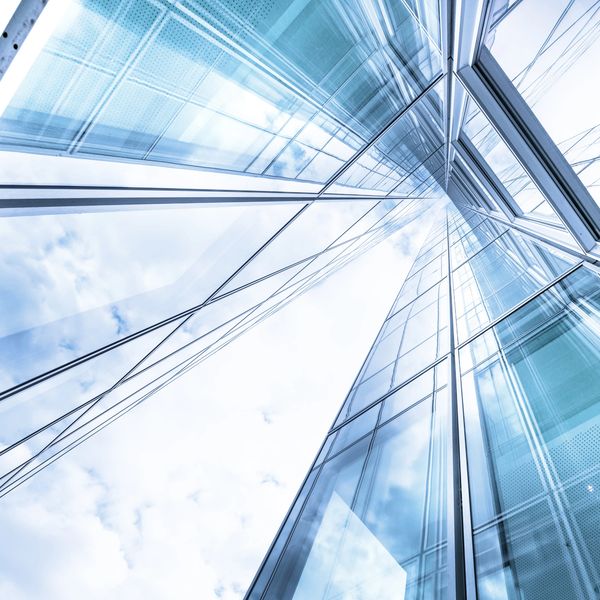 Looking up at a modern glass skyscraper reflecting the sky.