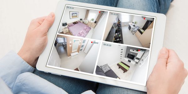 Person monitoring home security cameras on a tablet.