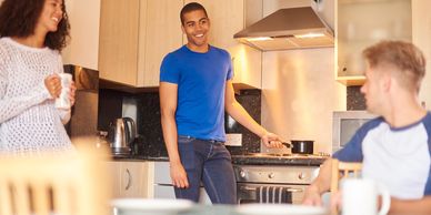 Three friends chatting and cooking together in a modern kitchen.