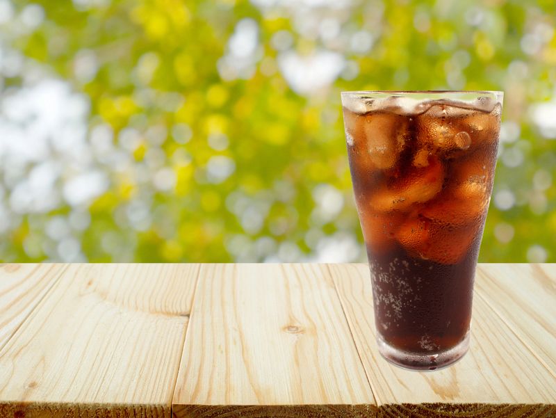 A glass of cola with ice cubes on a table with copy space for product display