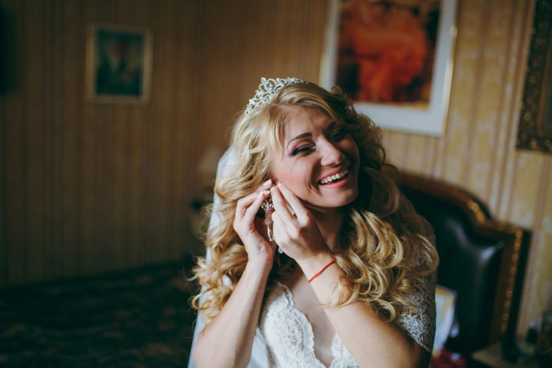 The beautiful bride blonde puts on her earrings