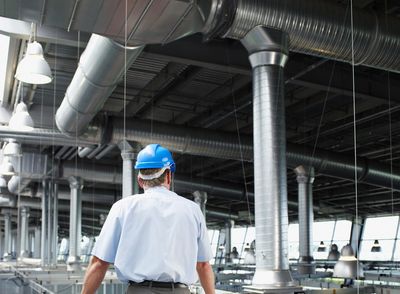 Engineer in a blue helmet inspects industrial facility.