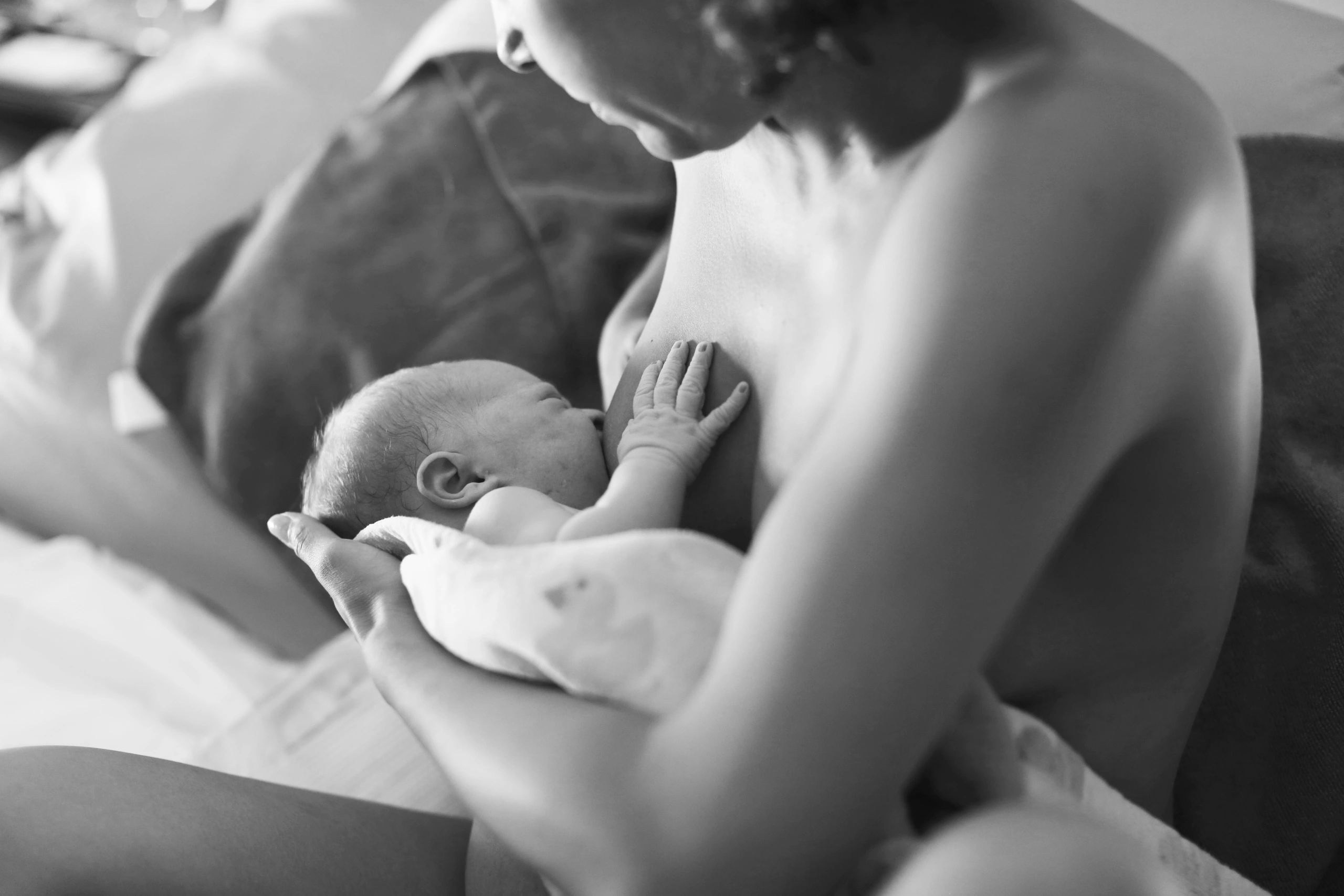 Black and white photo of a mother breastfeeding her newborn baby tenderly.