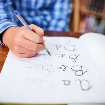 Child practicing handwriting in a notebook with a blue pen.