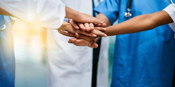 Medical team stacking hands in unity and support.