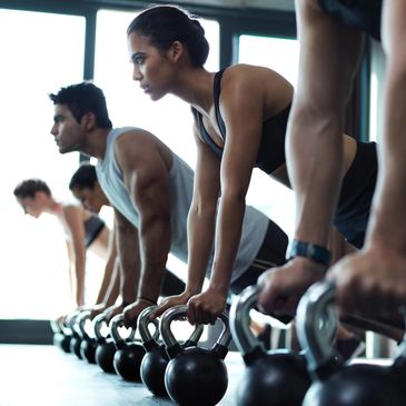Group doing push-ups using kettlebells in a gym class.