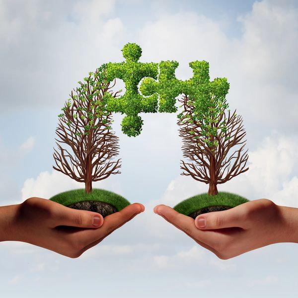 Two hands holding trees with green puzzle piece foliage connecting above them.